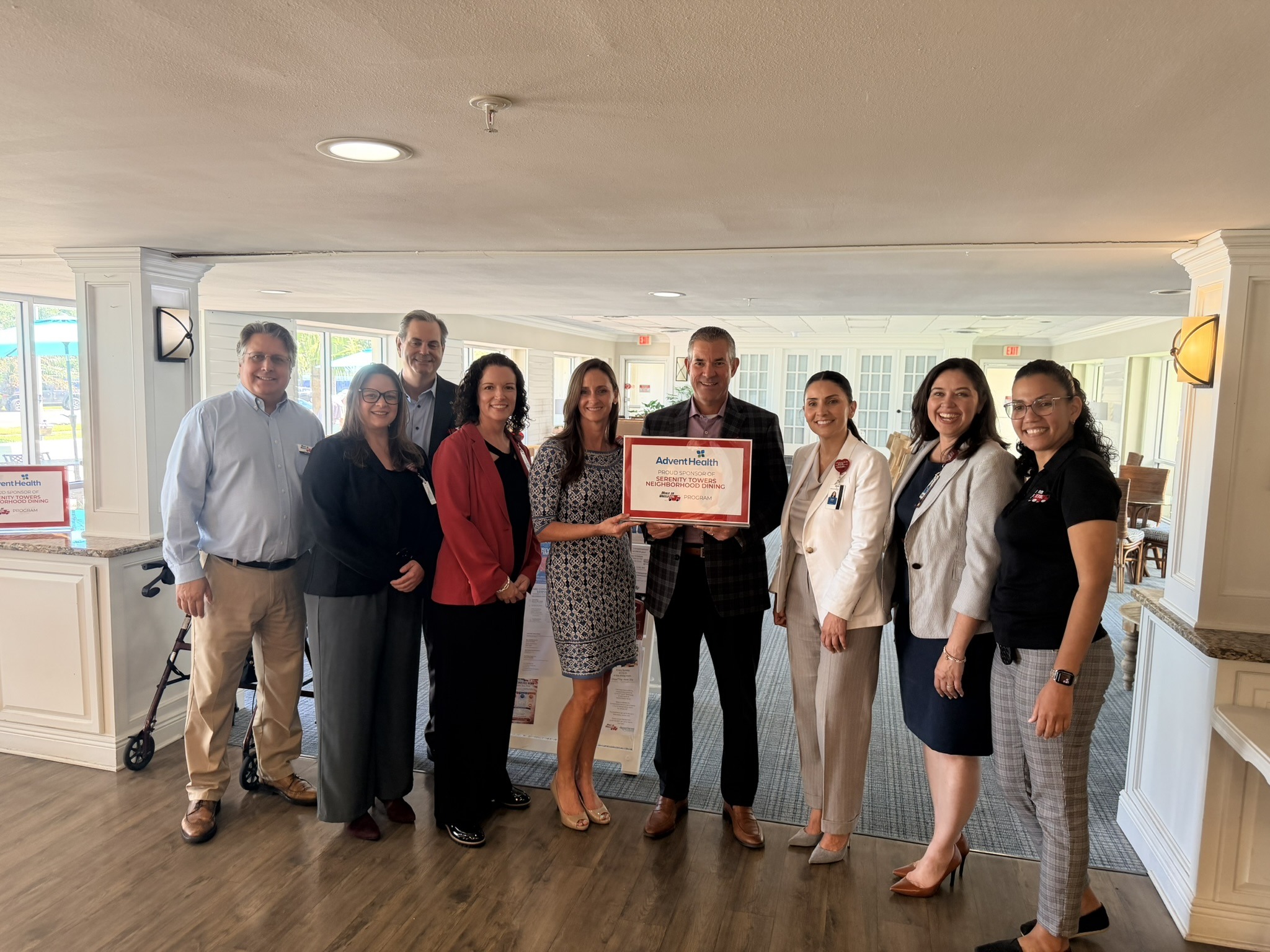Professionals from AdventHealth gather to celebrate the launch of a new community health program, holding a certificate in a well-lit venue.