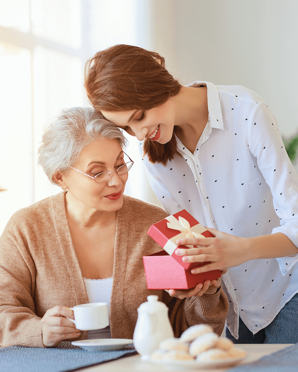 adult daughter gives gift and congratulates an elderly mother